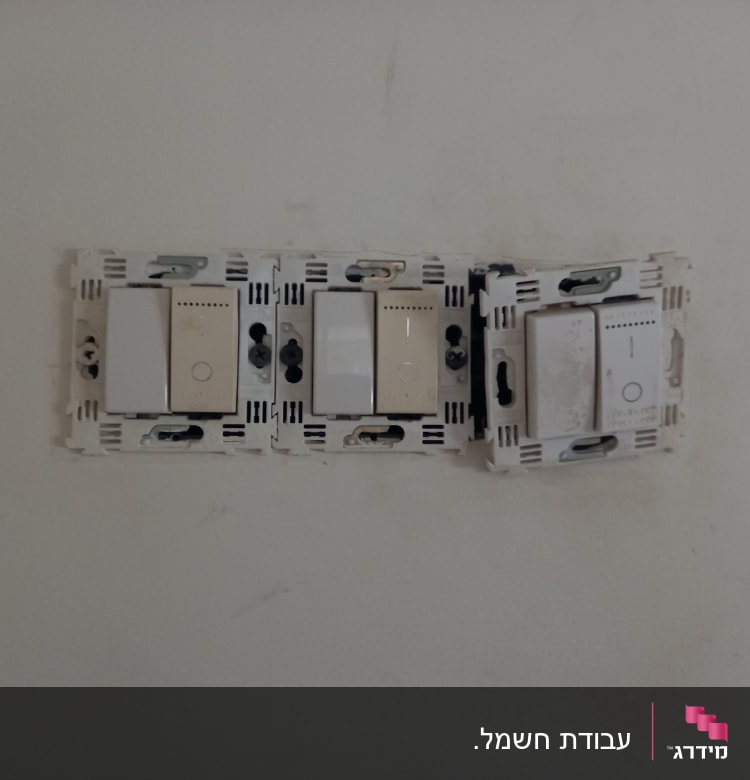 שלושה מתגים חשמליים מותקנים על קיר